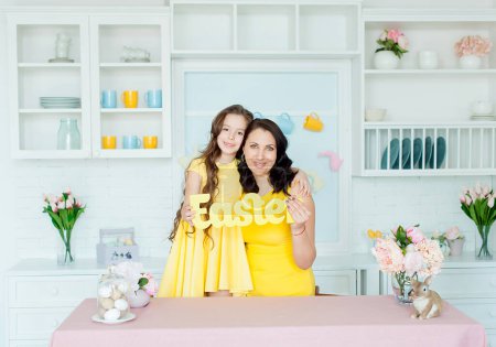 Foto de Easter card. Mother and daughter together at home Easter celebration sitting looking camera - Imagen libre de derechos