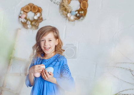 Téléchargez les photos : Happy Easter. A cute girl holds colored eggs in her hands and smiles cheerfully. Space for text. - en image libre de droit