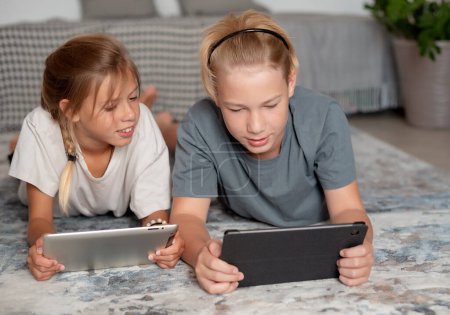 Téléchargez les photos : Deux enfants utilisant la tablette pc. Famille avec tablette dans la chambre. Enfants mignons utilisant des appareils - en image libre de droit