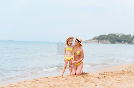 Téléchargez les photos : Mère fille s'amuser se reposant sur la plage - en image libre de droit