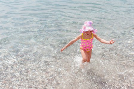 Téléchargez les photos : Adorable petite fille souriante heureuse en vacances à la plage - en image libre de droit