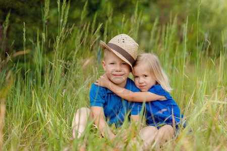 Téléchargez les photos : Portrait d'adorable frère et sœur sourire et rire ensemble tout en étant assis à l'extérieur. mode de vie heureux enfants - en image libre de droit