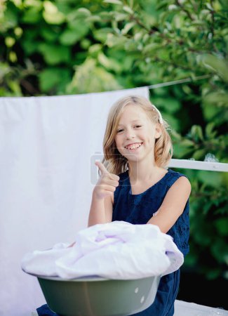 Téléchargez les photos : Little girl are having fun and smiling while doing laundry - en image libre de droit