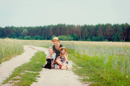 Téléchargez les photos : Belle famille heureuse s'amuse avec chiot en plein air - en image libre de droit