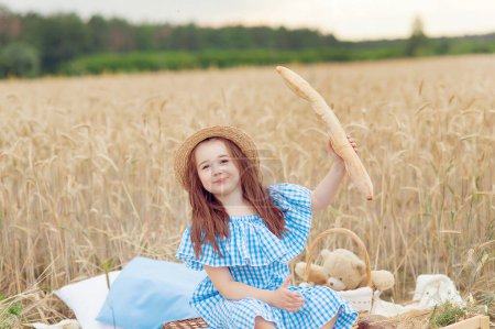 Téléchargez les photos : Petite belle fille souriante sur un champ de blé d'or. Les filles dans le champ de céréales. - en image libre de droit