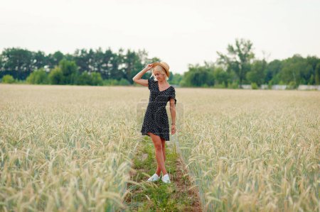 Photo for Portrait of a beautiful young woman in a dress walking through the wheat field - Royalty Free Image