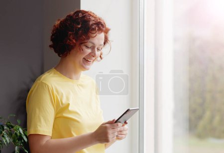 Photo for Happy girl holding cell phone using smartphone device at home. Smiling woman blogger subscribing new social media, buying in internet, ordering products online in apps. - Royalty Free Image