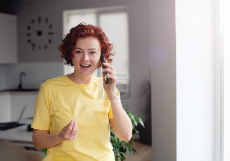 Foto de Image of joyful caucasian woman holding cellphone and gesturing - Imagen libre de derechos