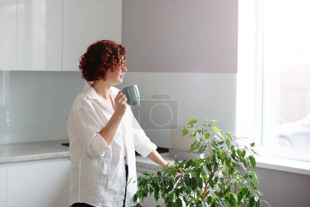 Téléchargez les photos : Portrait jeune femme dégustant une tasse de café à la maison. jolie fille boire du thé chaud - en image libre de droit
