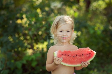 Photo for Cute little child girl eating watermelon fresh fruit in the garden - Royalty Free Image