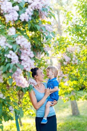 Téléchargez les photos : Heureuse femme et enfant dans le jardin fleuri du printemps. Fête des mères concept de vacances - en image libre de droit