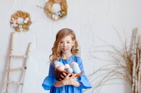 Foto de Cute little child on Easter day. Girl holding basket with painted eggs - Imagen libre de derechos