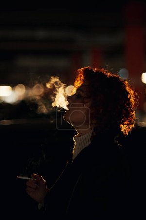 Photo for Silhouette of young woman smoking cigarette - Royalty Free Image