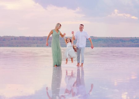 Foto de Feliz familia en la playa. Gente divirtiéndose en vacaciones de verano. Padre, madre e hijo contra el fondo del mar y del cielo. Concepto de viaje - Imagen libre de derechos