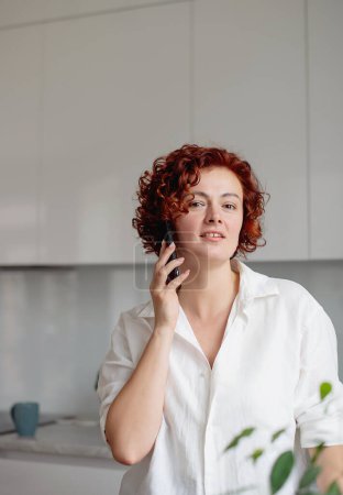 Photo for Happy woman talking on the phone at home, making answering call by cellphone beautiful lady having pleasant funny conversation speaking by mobile - Royalty Free Image