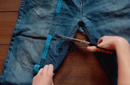 Téléchargez les photos : Denim Upcycling Ideas, Utilisation de vieux jeans, Repurposing Jeans, Réutilisation de vieux jeans, Upcycle Stuff. Femme couturière couper et réparer vieux jeans bleus. - en image libre de droit
