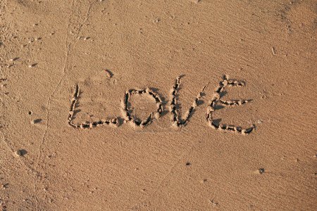 Téléchargez les photos : Des mots écrits dans du sable de plage. Le mot AMOUR écrit dans le sable sur la plage avec l'océan comme arrière-plan. - en image libre de droit