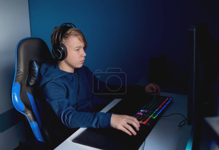 Téléchargez les photos : Jeune joueur jouant des jeux vidéo en ligne. Les jeunes accros aux nouvelles technologies - en image libre de droit