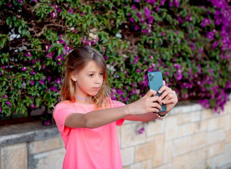Photo for Young girl take selfie from hands with phone on summer city street. - Royalty Free Image