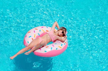 Téléchargez les photos : Fille sur anneau gonflable dans la piscine. Vacances - en image libre de droit