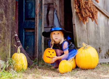 Foto de Divertido niño en traje de bruja para Halloween con calabazas - Imagen libre de derechos