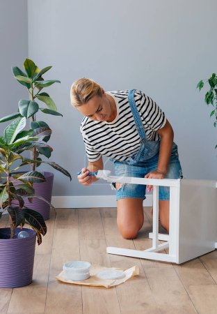 Téléchargez les photos : Femme à la maison peignant une chaise ou peignant comme upcycling - en image libre de droit