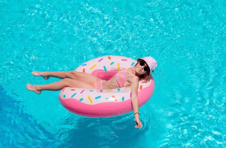 Foto de Joven chica sonriente equipado en bikini, sombrero relajarse en inflable en la piscina. chica tomando el sol en resort de lujo - Imagen libre de derechos