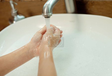 Foto de Niño lavándose las manos con agua y jabón en el baño. Higiene de las manos y prevención de infecciones virales - Imagen libre de derechos