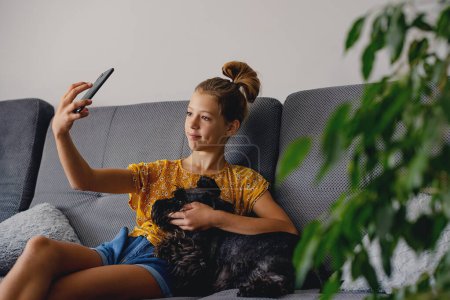Photo for Friendship Concept. teenager girl caucasian taking selfie with her dog at home - Royalty Free Image