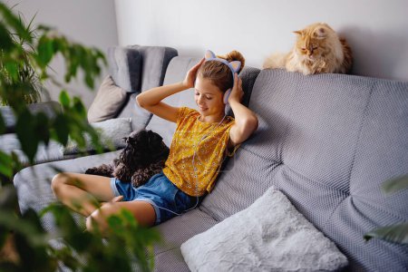 Foto de Hogar, tecnología y concepto de música - chica adolescente con auriculares en casa - Imagen libre de derechos