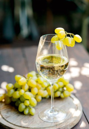 Téléchargez les photos : Verre avec vin blanc sur un tonneau en bois dans le vignoble. - en image libre de droit