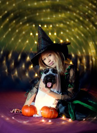 Foto de Chica vistiendo a su perro en traje de murciélago de Halloween. chica con mascota en el interior que componen trajes de fiesta para una fiesta en casa - Imagen libre de derechos