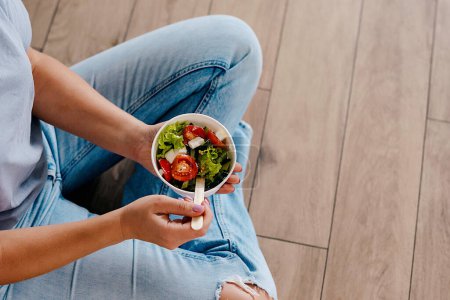 Photo for Woman eating healthy salad from paper container - Royalty Free Image