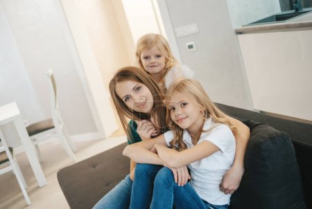 Téléchargez les photos : Famille à la maison s'amuser. mère et filles riant sur le canapé - en image libre de droit