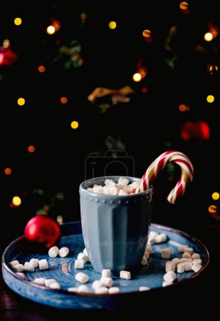 Foto de Copa de Navidad de cacao con malvaviscos sobre el fondo de un árbol de Navidad. El humor de Año Nuevo - Imagen libre de derechos