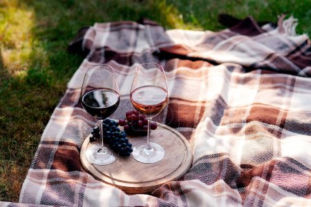Téléchargez les photos : Deux verres de vin blanc et une assiette en bois avec fromage et raisins servis à l'extérieur - en image libre de droit