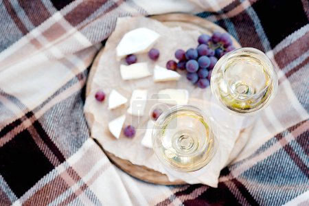 Photo for Two glasses of white wine and a wooden plate with cheese and grapes served outside - Royalty Free Image