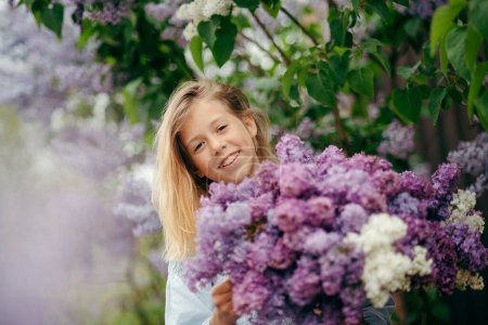 Téléchargez les photos : Belle jeune fille avec un bouquet de lilas, une fille en lilas, lilas au printemps. Jeune fille posant avec un bouquet de lilas - en image libre de droit