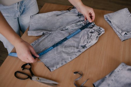 Photo for Denim Upcycling Ideas, Using Old Jeans, Repurposing Jeans, Reusing Old Jeans, Upcycle Stuff. Woman seamstress cut and repair old jeans in sewing studio. - Royalty Free Image