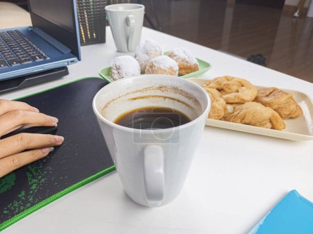 Photo for A young woman drank a glass of coffee accompanied by snacks during breaks during work time. - Royalty Free Image