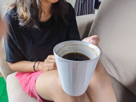 Photo for A young woman drank a glass of coffee on the sofa while relaxing. Christmas and New Year holidays - Royalty Free Image
