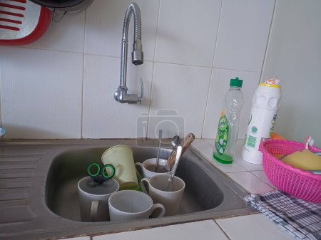 Photo for Dirty dishes and glasses in the sink that have not been washed. Piles of dirty dishes and glasses that haven't been washed, real life at the end of the year - Royalty Free Image
