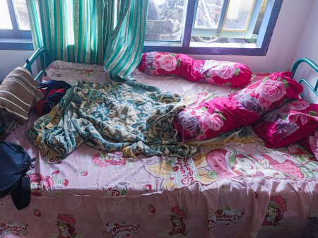 Photo for The bedroom is a mess. A child's room with a messy bed and pillows, bolsters and quilts that have not been tidied up. real life. - Royalty Free Image