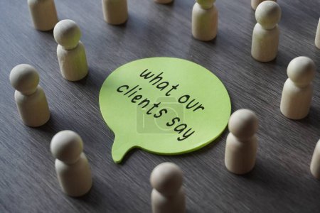 Photo for A group of wooden figurines surrounding a speech bubble with text WHAT OUR CLIENTS SAY. Business, feedback concept - Royalty Free Image