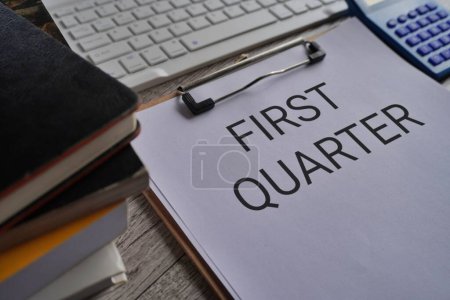 Photo for Close up image of paper clipboard with text FIRST QUARTER on office desk - Royalty Free Image