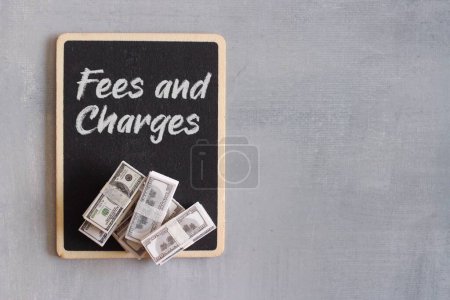 Photo for Top view image of money and chalkboard with text FEES AND CHARGES, Business and finance concept - Royalty Free Image