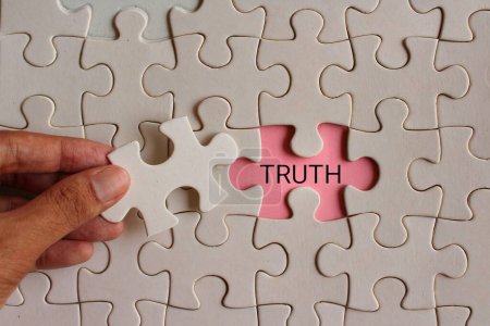Closeup image of hand pickup puzzle and reveal the word TRUTH. 