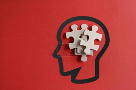 Verstreute Rätsel im menschlichen Kopf mit Kopierraum auf rotem Hintergrund. Autismus, Down-Syndrom, Stress und Denkmuster 