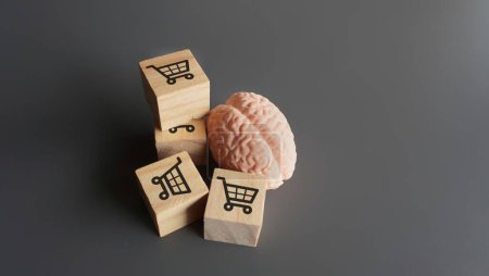Téléchargez les photos : Un cerveau humain et des blocs de bois avec une icône de chariots. Comportement des consommateurs, achat impulsif et concept de dépendance au shopping. - en image libre de droit