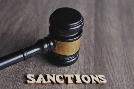 Photo for Close up image of judge gavel and text SANCTIONS on wooden table. - Royalty Free Image